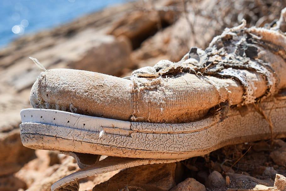 Zapato viejo y sucio visto de cerca en una playa.