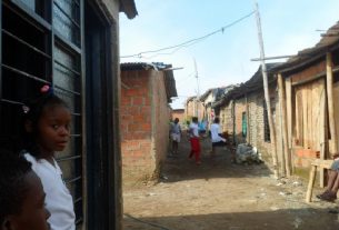Paisaje de Brisas de Comuneros en 2014; una niña afro mira la cámara mientras unos jóvenes juegan en el fondo.