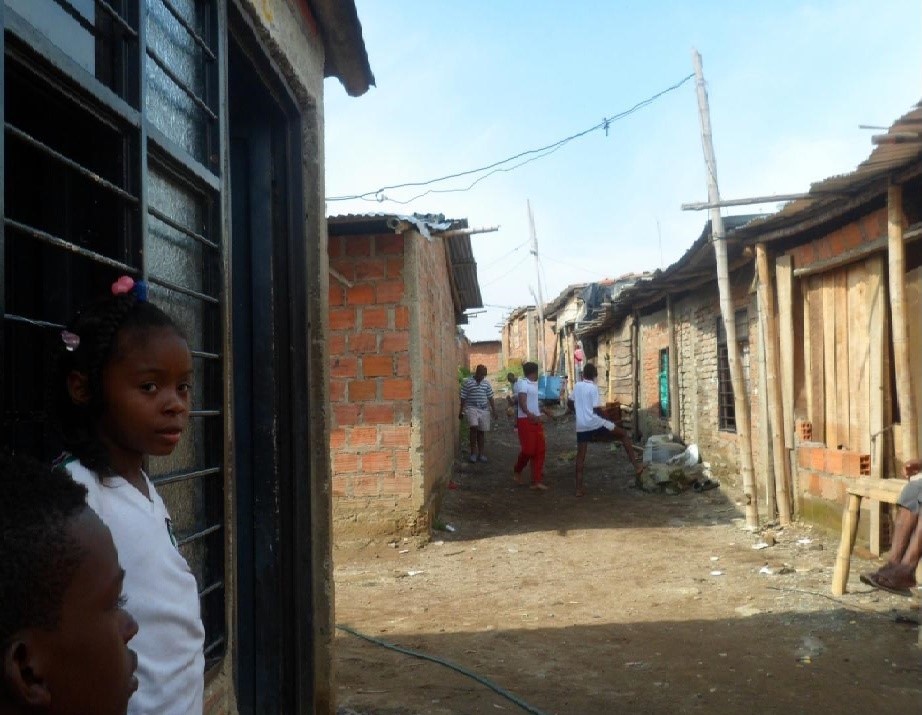 Paisaje de Brisas de Comuneros en 2014; una niña afro mira la cámara mientras unos jóvenes juegan en el fondo.