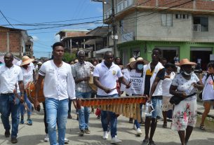 Dos jóvenes sostienen una marimba para que se pueda tocar en una de las marchas por las comunidades en apoyo al Pacto por la Vida y por la Paz.