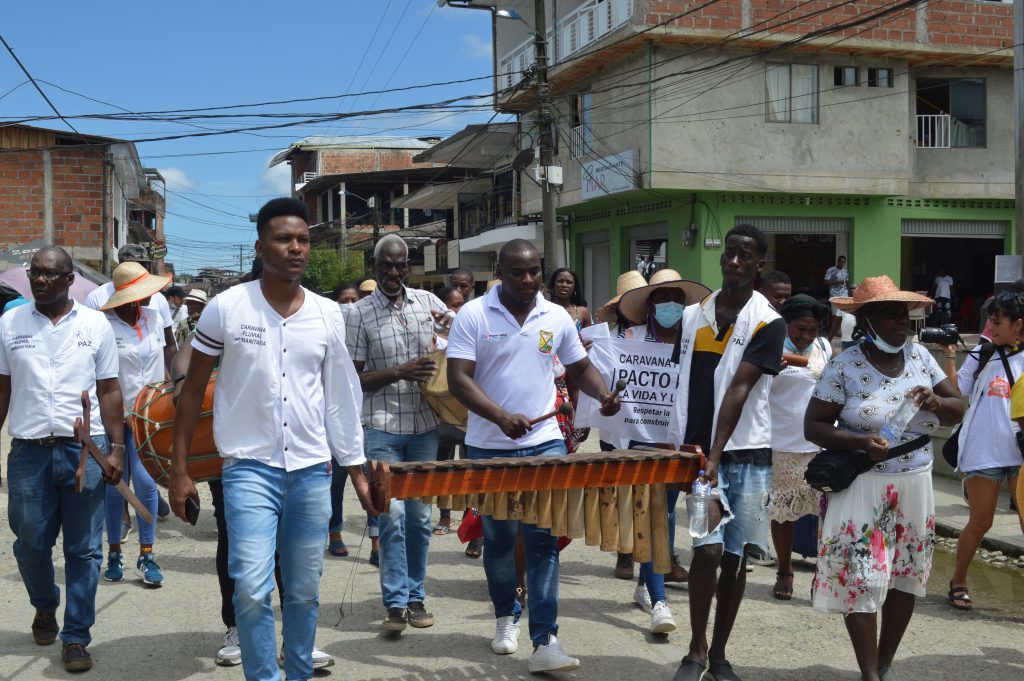 Dos jóvenes sostienen una marimba para que se pueda tocar en una de las marchas por las comunidades en apoyo al Pacto por la Vida y por la Paz.